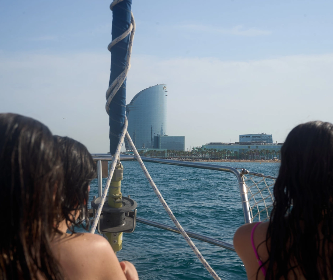 Grupo de personas disfrutando de una salida en velero de lujo navegando cerca de la ciudad al atardecer