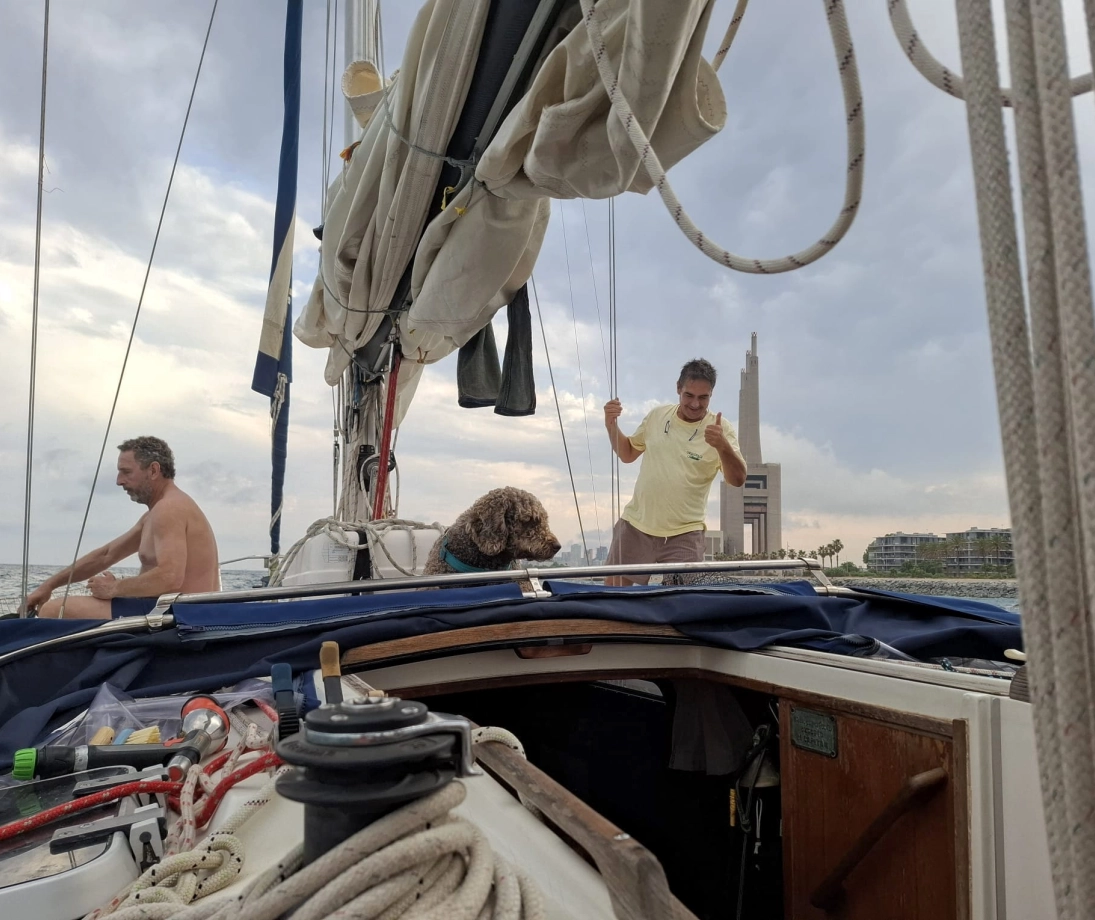 Grupo de personas disfrutando de una salida en velero de lujo navegando cerca de la ciudad al atardecer