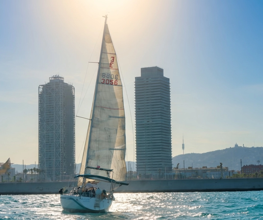 Grupo de personas disfrutando de una salida en velero de lujo navegando cerca de la ciudad al atardecer