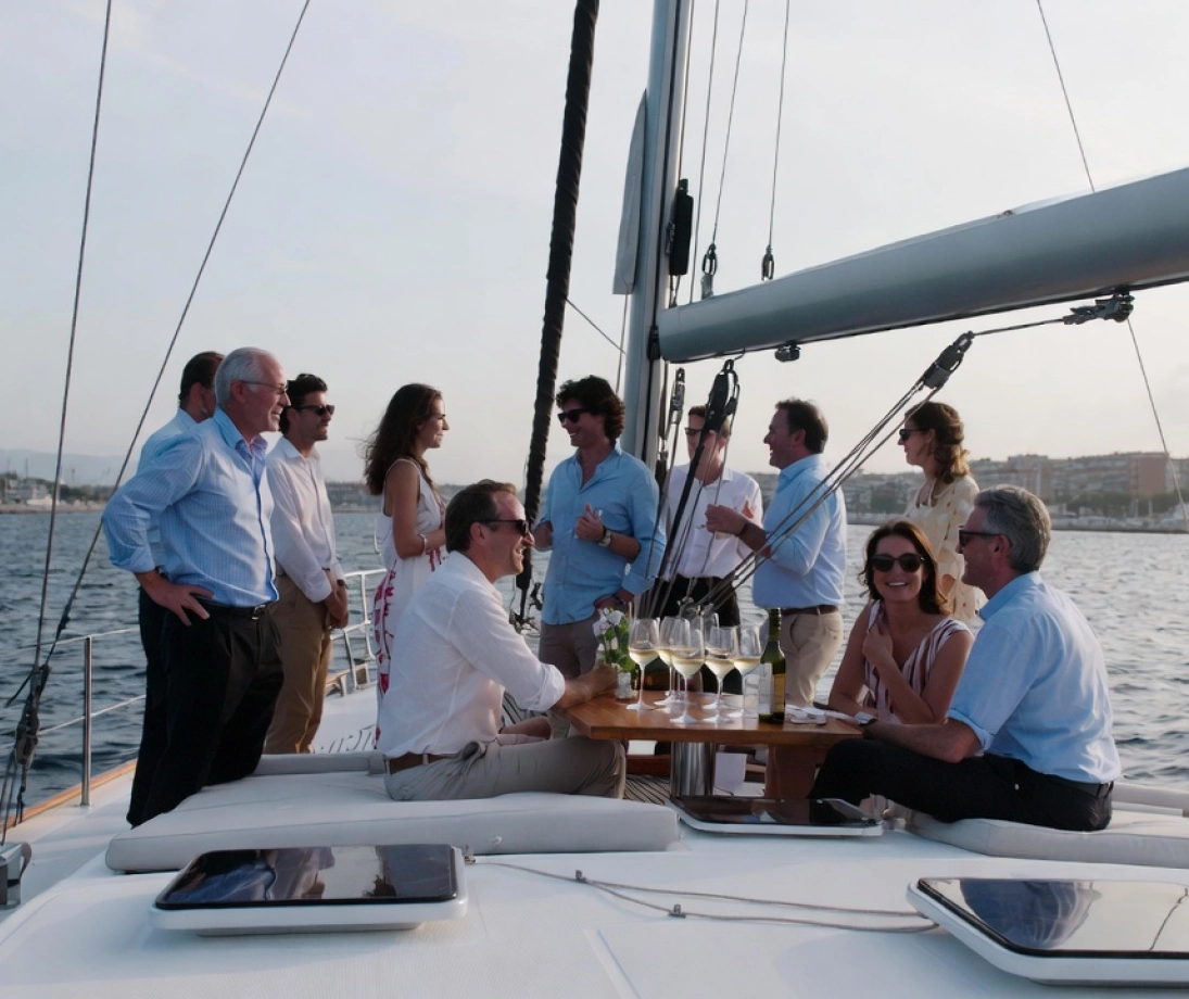 Gruppo di persone che si godono un’uscita in barca a vela di lusso navigando vicino alla città al tramonto