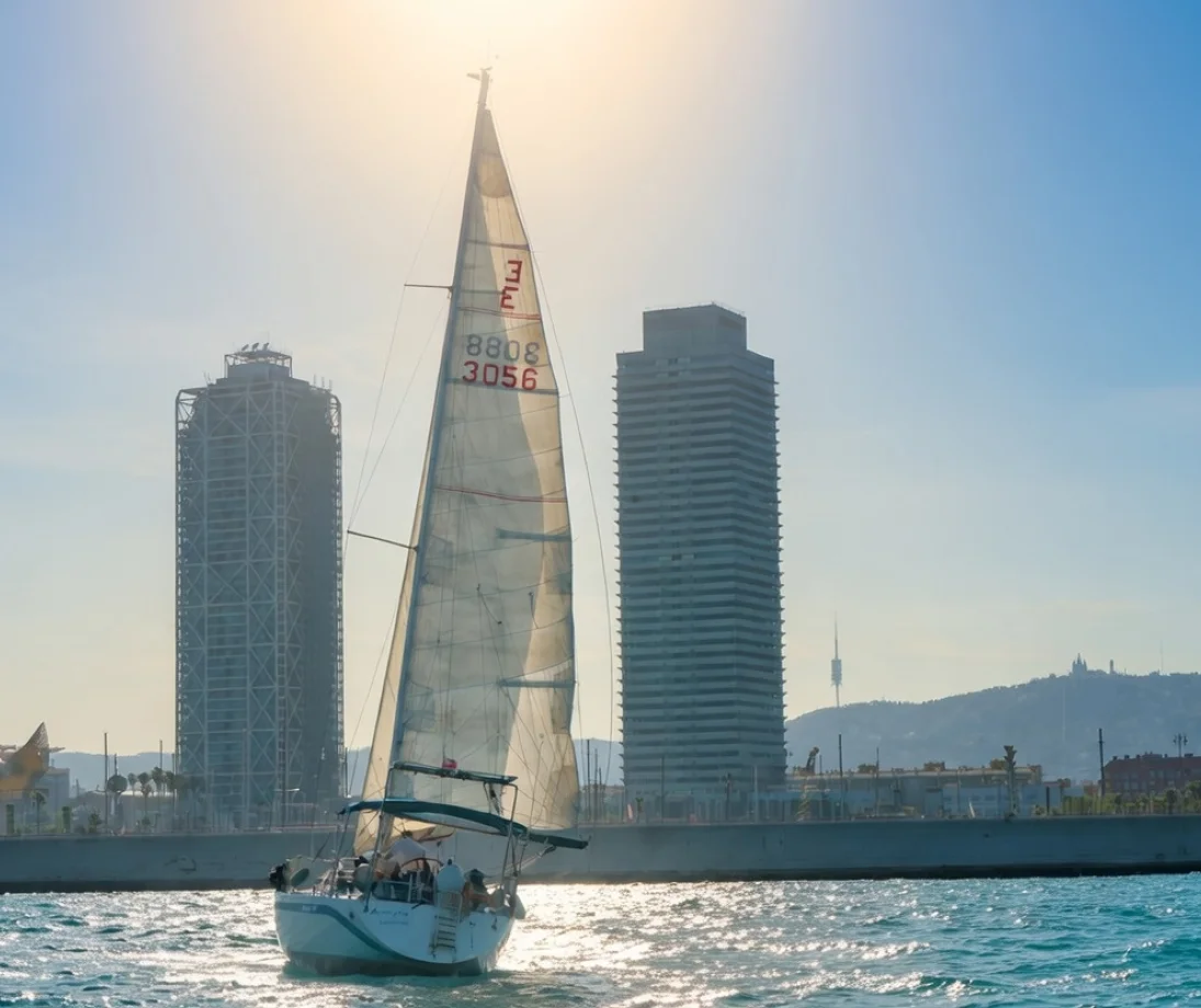 Tre persone che parlano rilassate su uno yacht di lusso di fronte allo skyline di Barcellona al tramonto