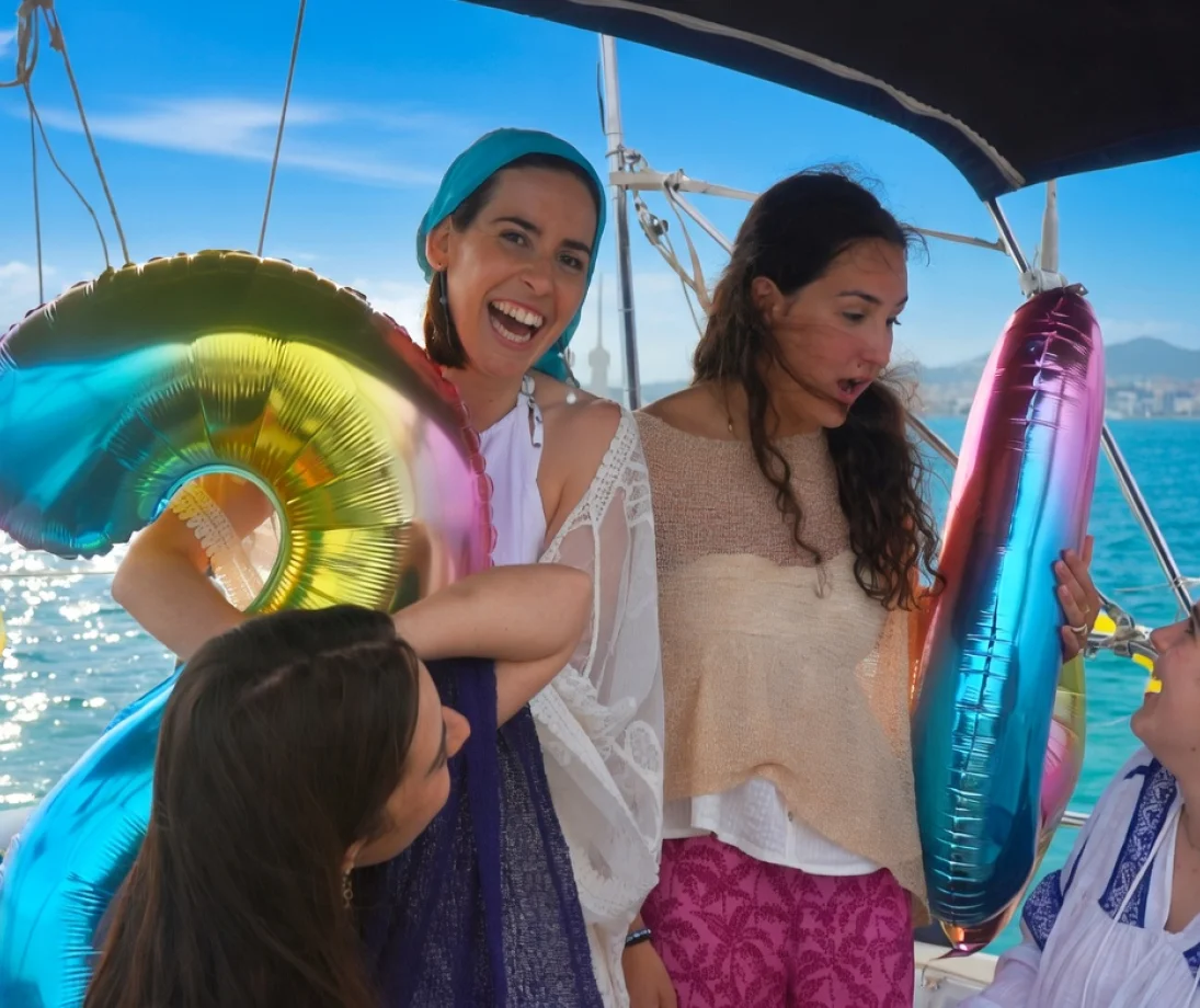 Trois personnes discutant tranquillement sur un voilier de luxe face à la skyline de Barcelone au coucher du soleil