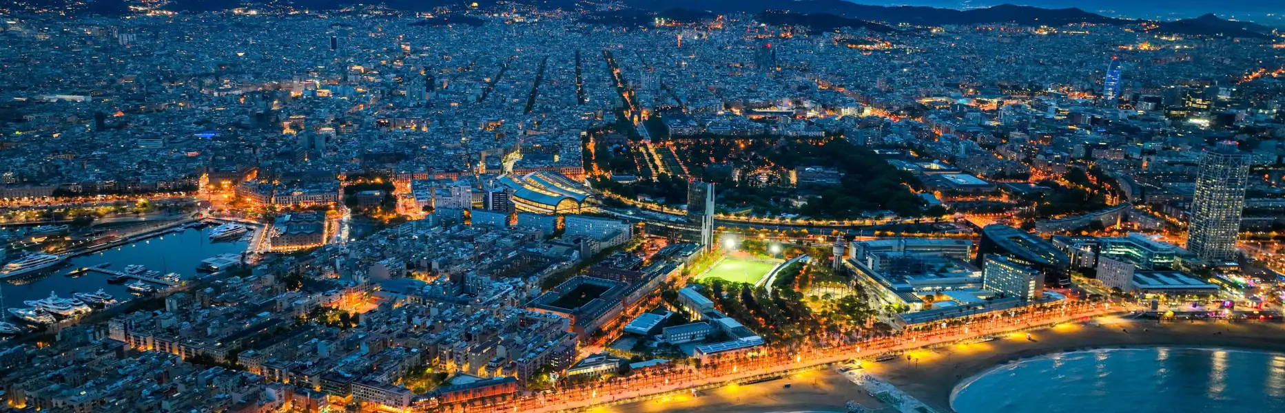Vue aérienne de Barcelone au coucher du soleil avec les lumières de la ville et la côte illuminée le long de la mer