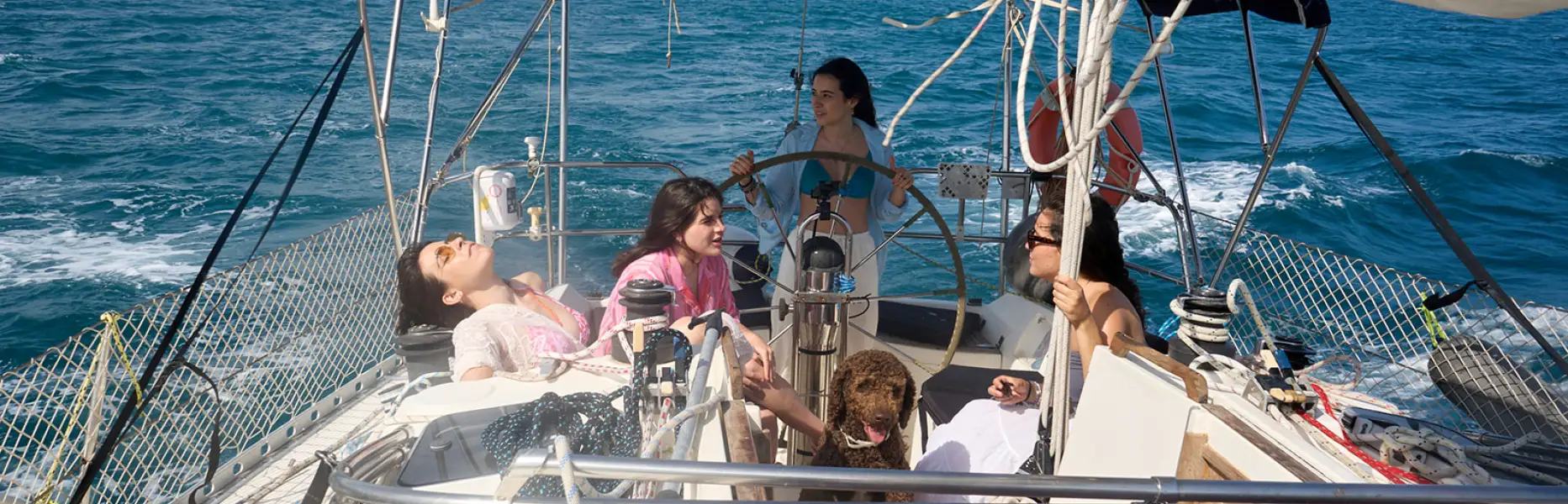 Gruppe von Freundinnen, die sich auf dem Deck einer Segelyacht während eines privaten Charters vor der Küste Barcelonas entspannt