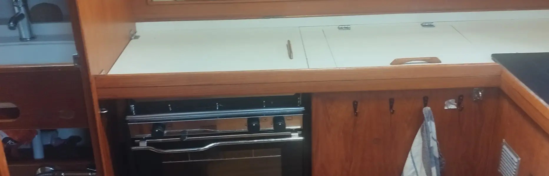 Cuisine en bois entièrement équipée à l’intérieur d’un voilier privé à Barcelone, avec four, évier et torchon suspendu
