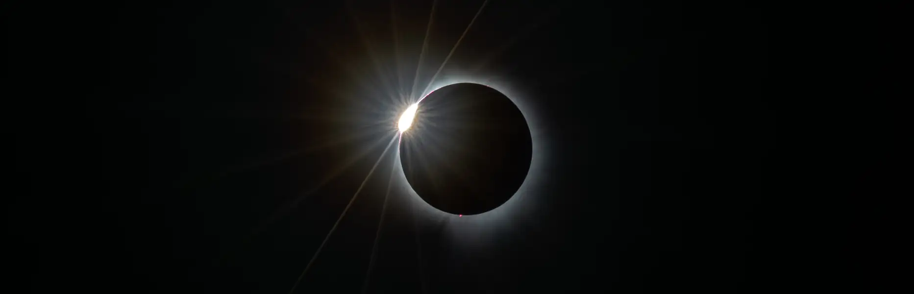 Diamond ring phase of the total solar eclipse with a bright corona on a black background