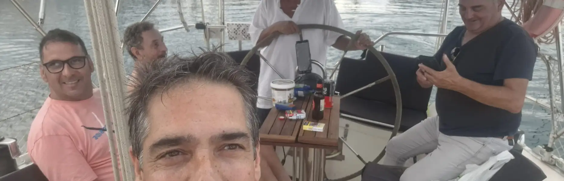 Gruppo di cinque uomini rilassati sul ponte di un veliero ormeggiato alla Marina Badalona
