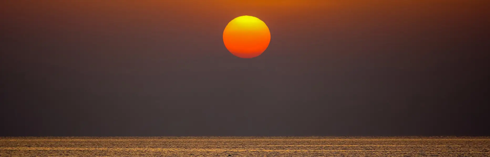 Aufgang der Sonne über einem ruhigen Meer bei einem Sonnenaufgang in Barcelona, gesehen von einer Segelyacht aus