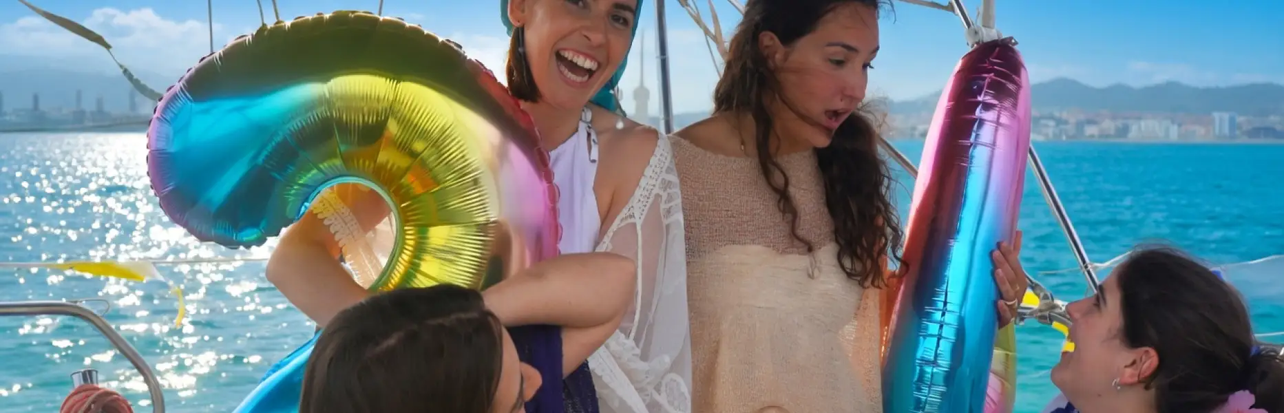 Small group of friends enjoying a boat trip past the Barcelona skyline with colourful balloons