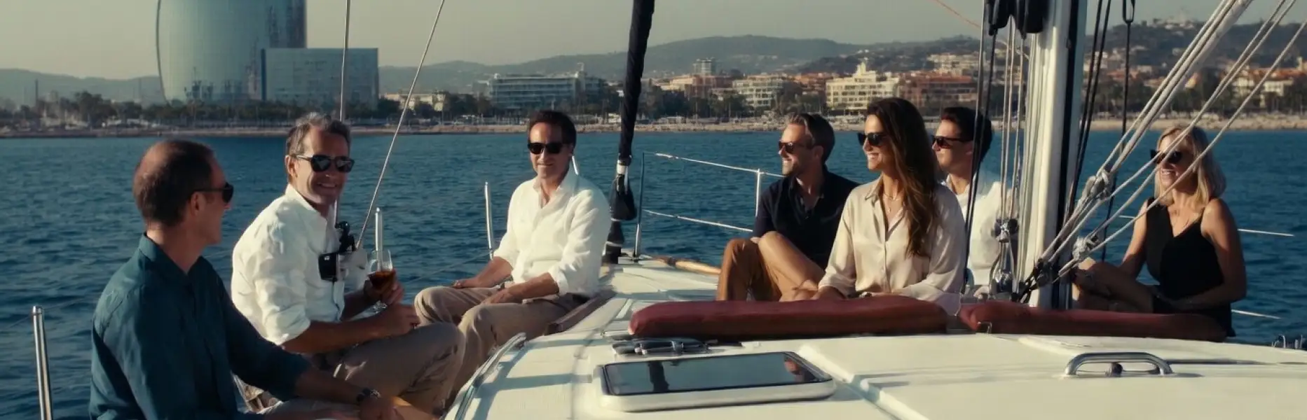 Grupo de amigos disfrutando de un charter de lujo en velero frente a la costa de Barcelona en un día soleado