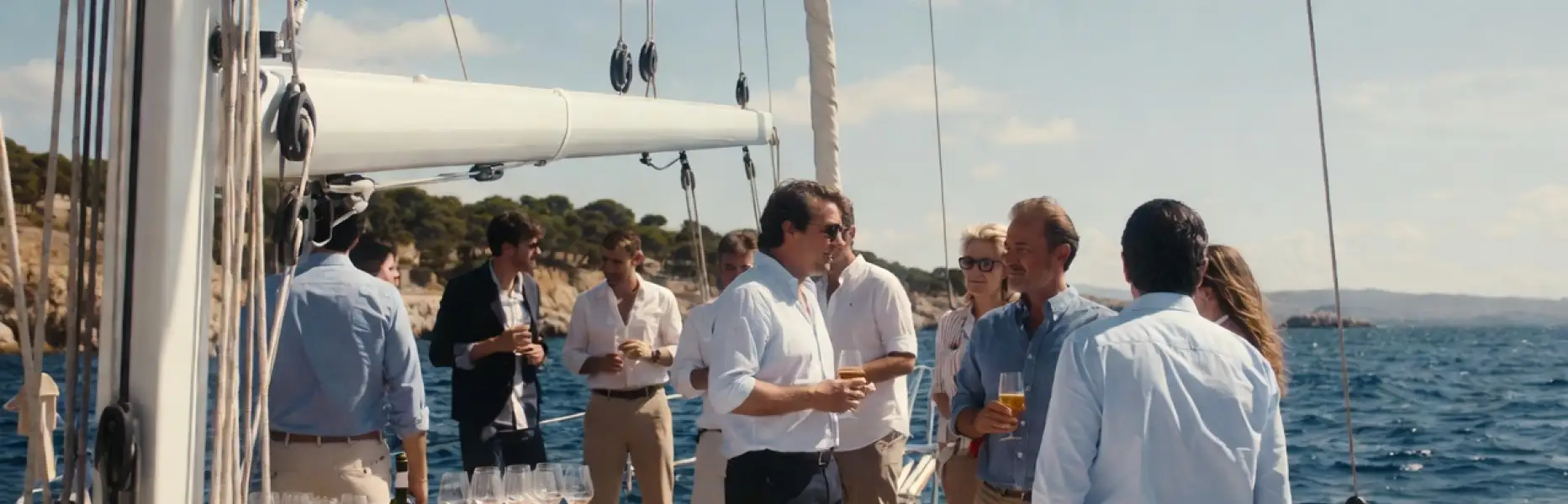 Grupo de personas disfrutando de un charter de lujo en velero privado sobre el mar en un día soleado