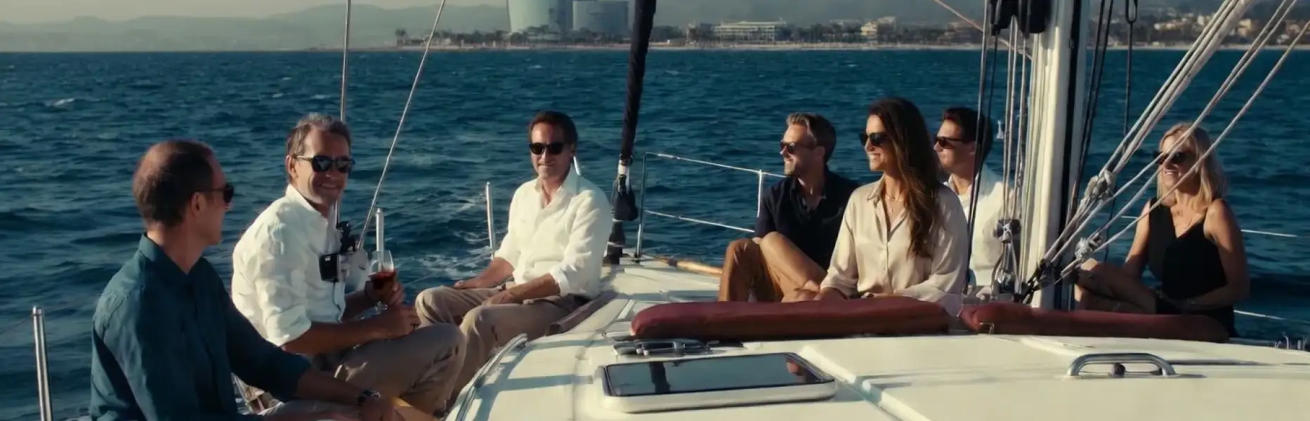 Grupo de amigos disfrutando de un charter de lujo en velero frente a la costa de Barcelona