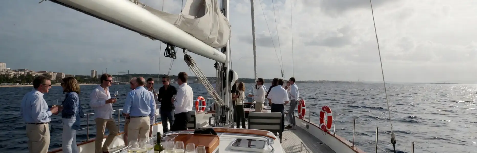 Gruppo di persone che si gode un charter di lusso in barca a vela con calici di vino sul mare