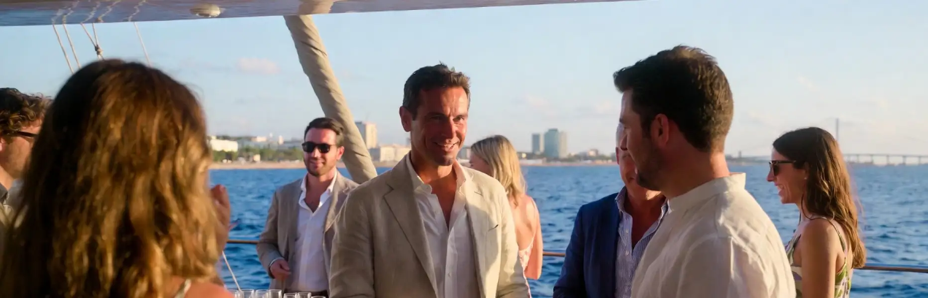 Grup de persones gaudint d’un esdeveniment de luxe en iot de lloguer al capvespre davant del mar