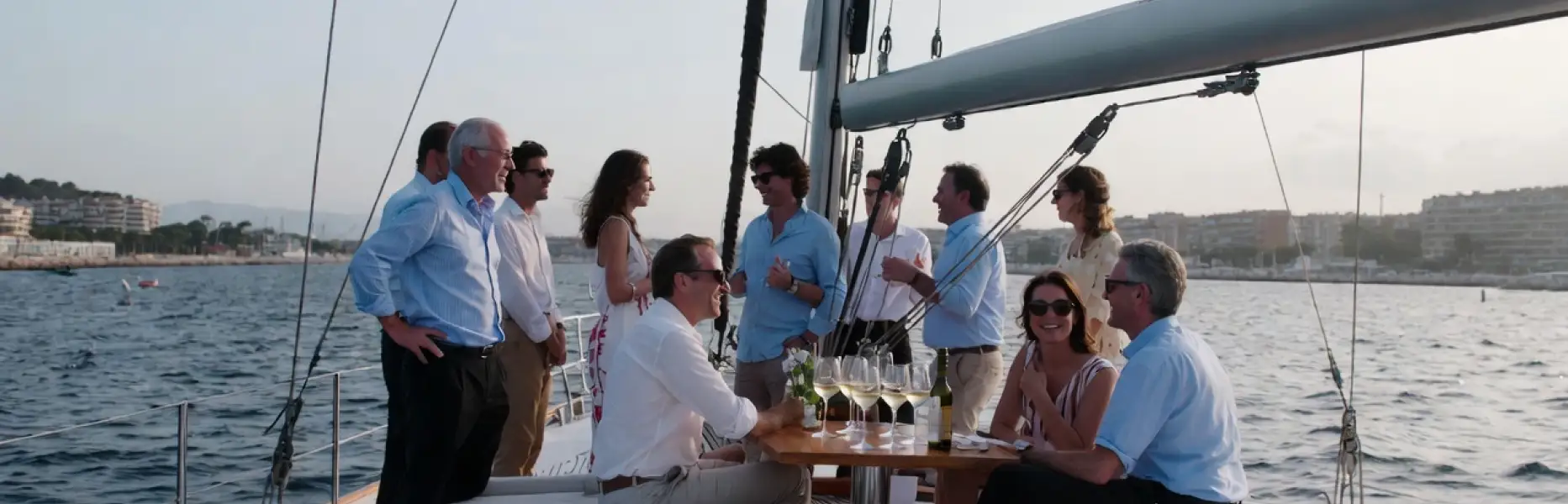 Grupo de personas disfrutando de un charter en yate de lujo al atardecer frente a la costa
