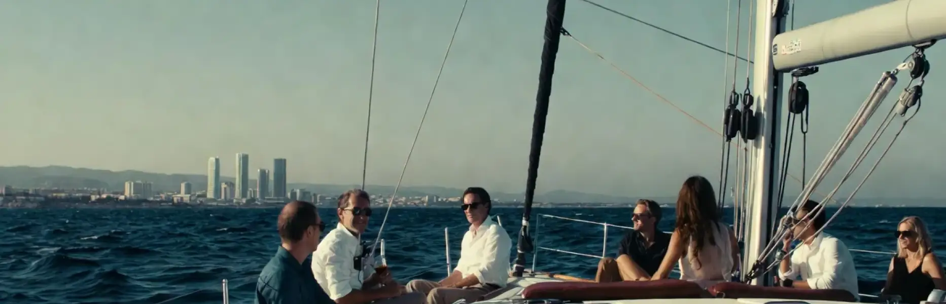 Gruppe von Personen, die einen Luxus-Segelcharter mit Blick auf die Stadt im Hintergrund genießt