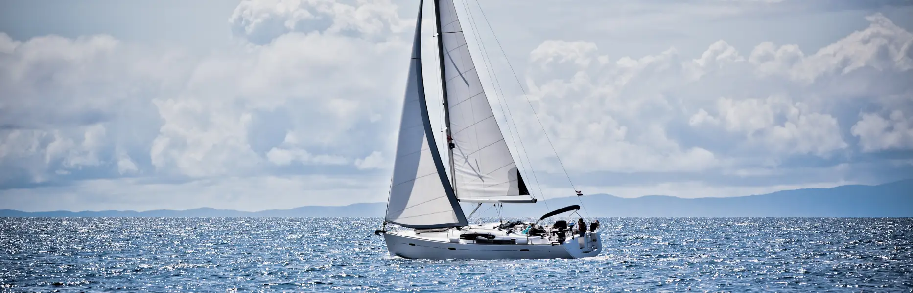Velero de charter navegando en grupo reducido frente al mar Mediterraneo en un dia despejado