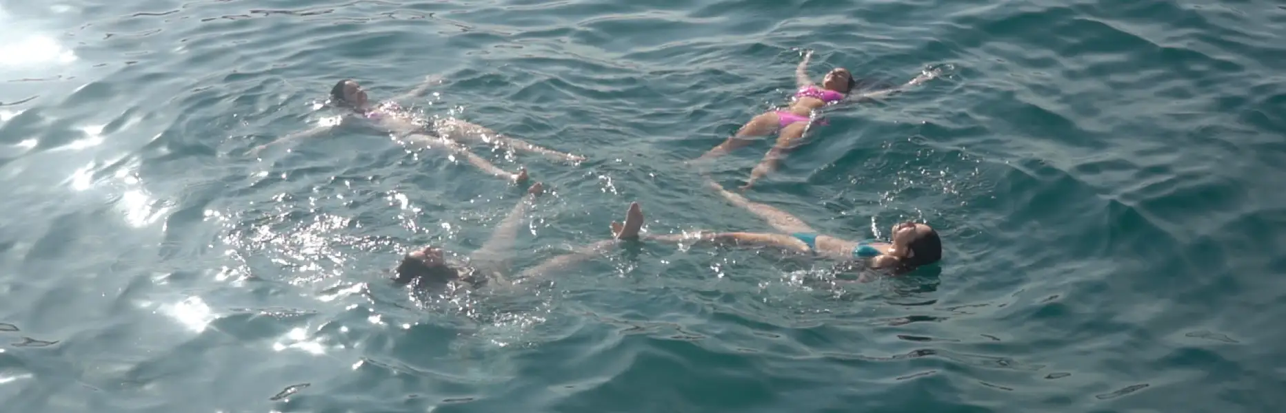 Grup de persones flotant relaxades al mar durant un passeig en vaixell al capvespre a Barcelona