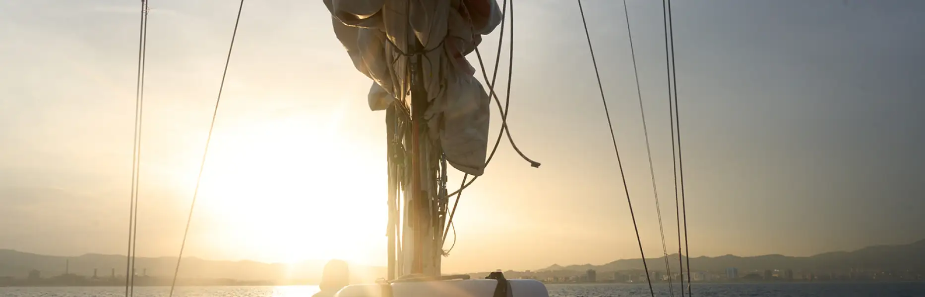 Sunset on a boat off the coast of Barcelona with the sun setting over the sea and the mountains in the background