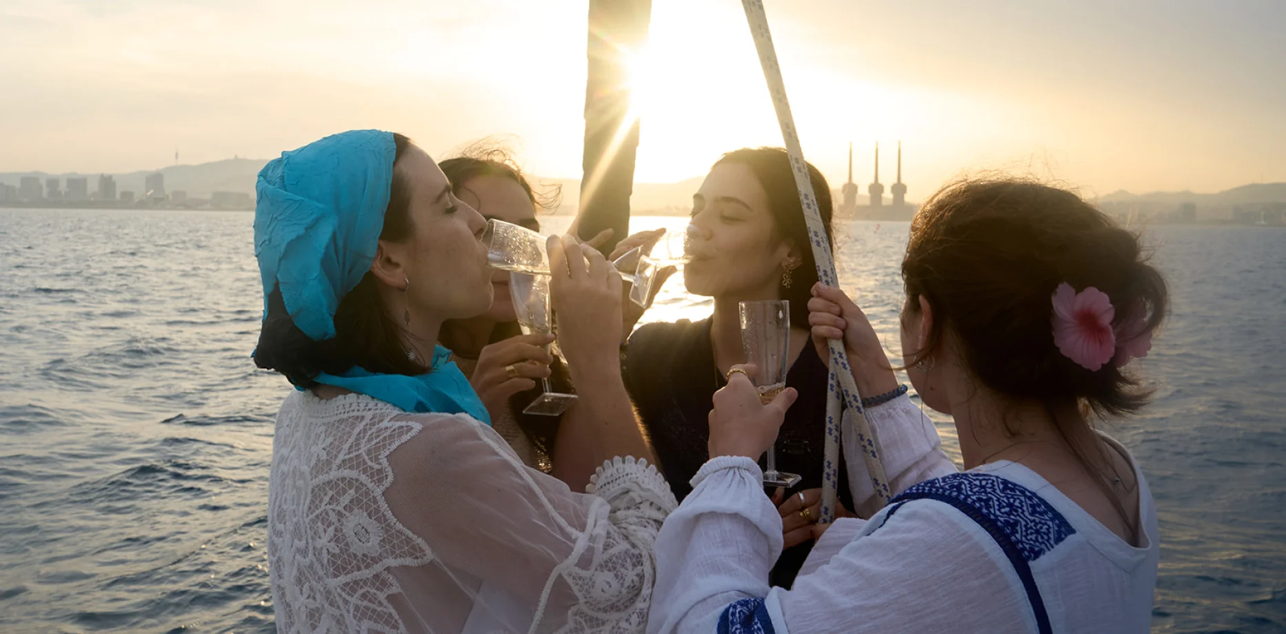 Grupo de amigos elegantes disfrutando de un charter en velero al atardecer en el mar