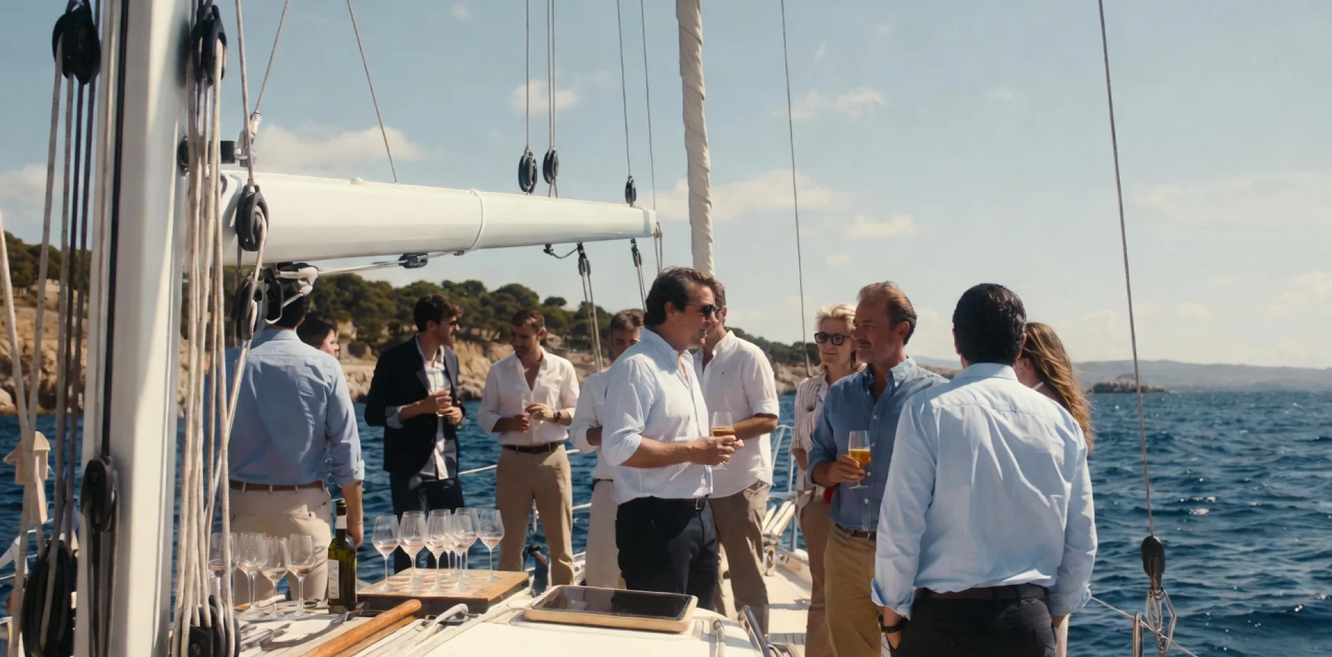 Grupo de amigos elegantes disfrutando de un charter en velero al atardecer en el mar