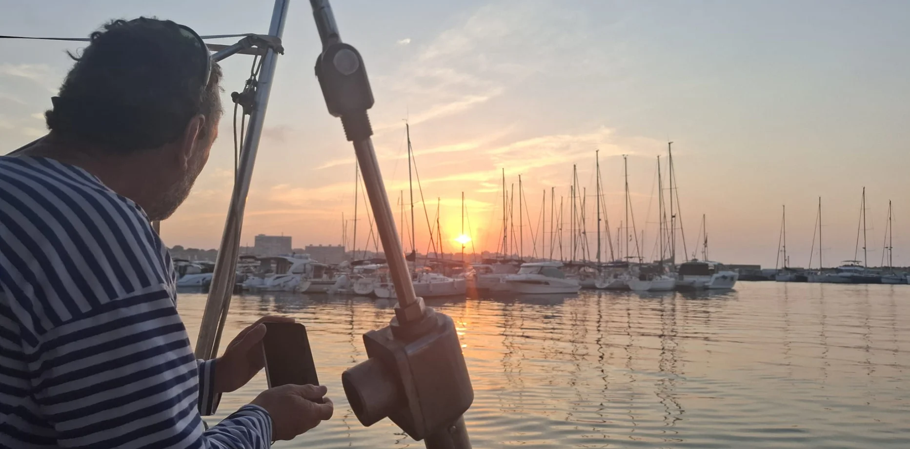 Groupe de professionnels dégustant du vin et des amuse-bouches sur un voilier face à la skyline de Barcelone au coucher du soleil