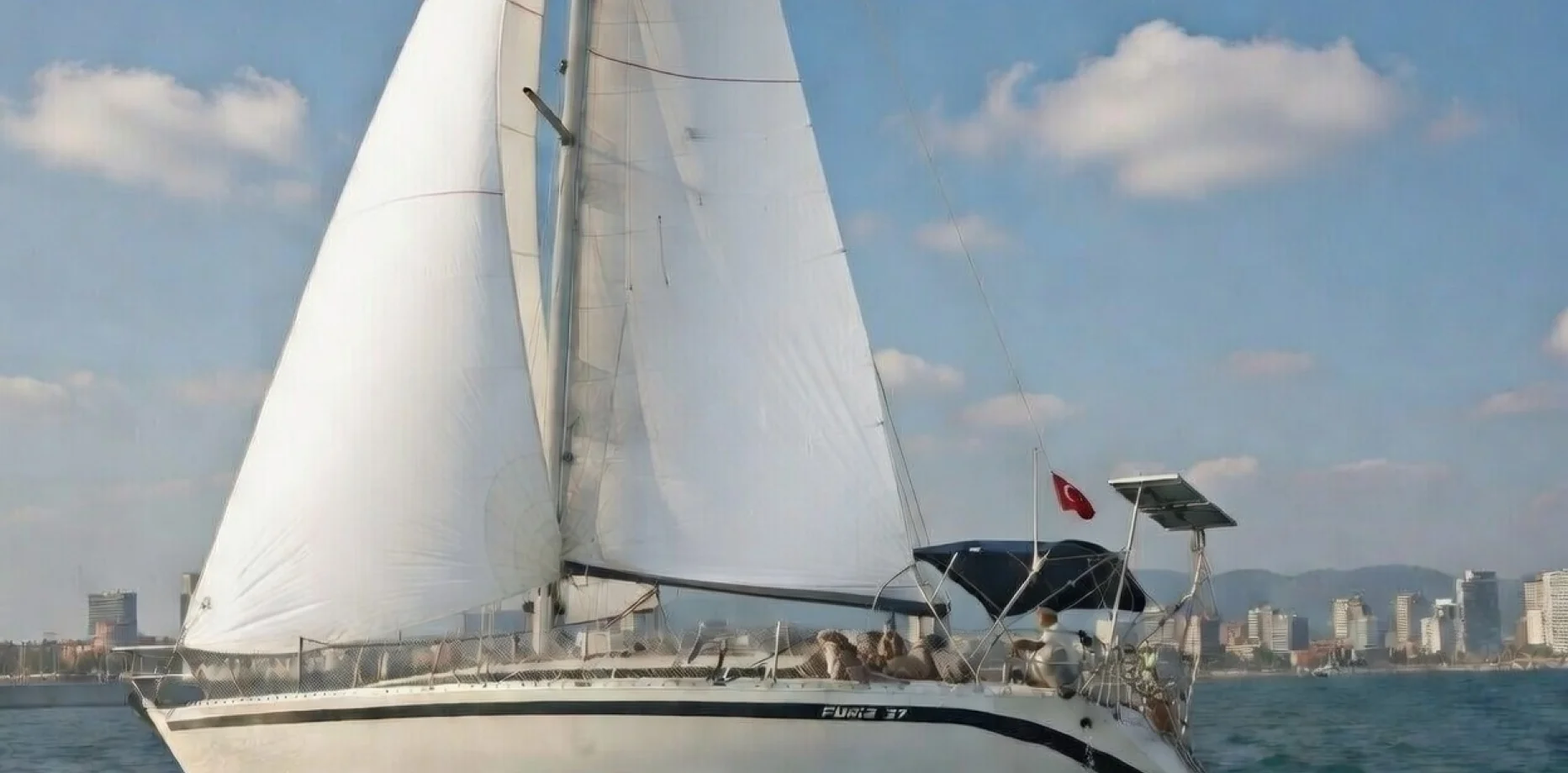 Gruppe eleganter Freunde, die bei Sonnenuntergang auf dem Meer einen Segelcharter genießen
