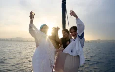 Group of friends toasting with cava at sunset on a boat in front of the Barcelona skyline