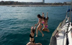 Drei Mädchen springen von einer Segelyacht ins Meer vor der Küste Barcelonas während eines privaten Charters