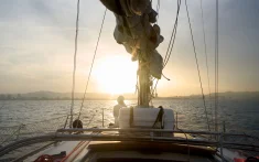View from the deck of a sailing boat at sunset in Barcelona with the sun over the sea