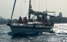 Gruppo di persone che si godono una gita in barca a vela al tramonto davanti alla costa di Barcellona