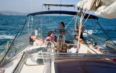 Grup d'amigues relaxant-se a la coberta d'un veler durant un xàrter privat davant la costa de Barcelona