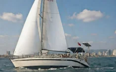 Veler navegant davant de l’skyline de Barcelona en un dia assolellat i amb la mar en calma