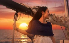 Mujer disfrutando de un amanecer en velero privado frente al mar en Barcelona