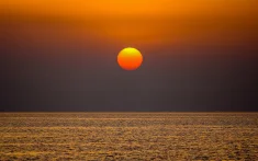 Sun rising over a calm sea during dawn in Barcelona, seen from a sailboat