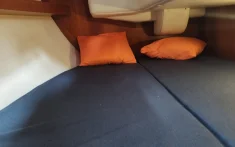 Double cabin on a private sailing boat with orange cushions and natural light in Barcelona