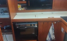 Cucina in legno completamente attrezzata all'interno di un veliero privato a Barcellona con forno, lavello e asciugamano appeso