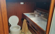Private bathroom on a sailboat with toilet, sink and towels in a wooden cabin