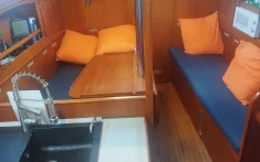 Interior acollidor de veler privat amb saló de fusta, coixins taronges i cuina equipada per a xàrter de dia complet a B