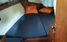 Camarote doble en velero con cama amplia y cojines naranjas para la expedición al eclipse total de Sol 2026 desde Barcelona