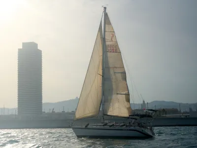 Velero de charter navegando frente al skyline de Barcelona Velero de charter navegando frente al skyline de Barcelona