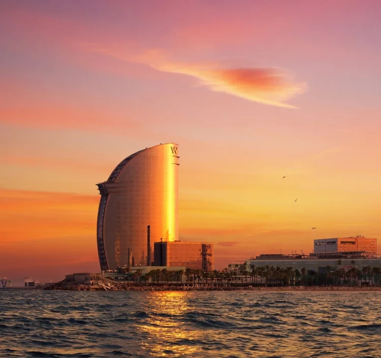 Golden sunrise over Barcelona’s W Hotel seen from the sea on a private sailing boat